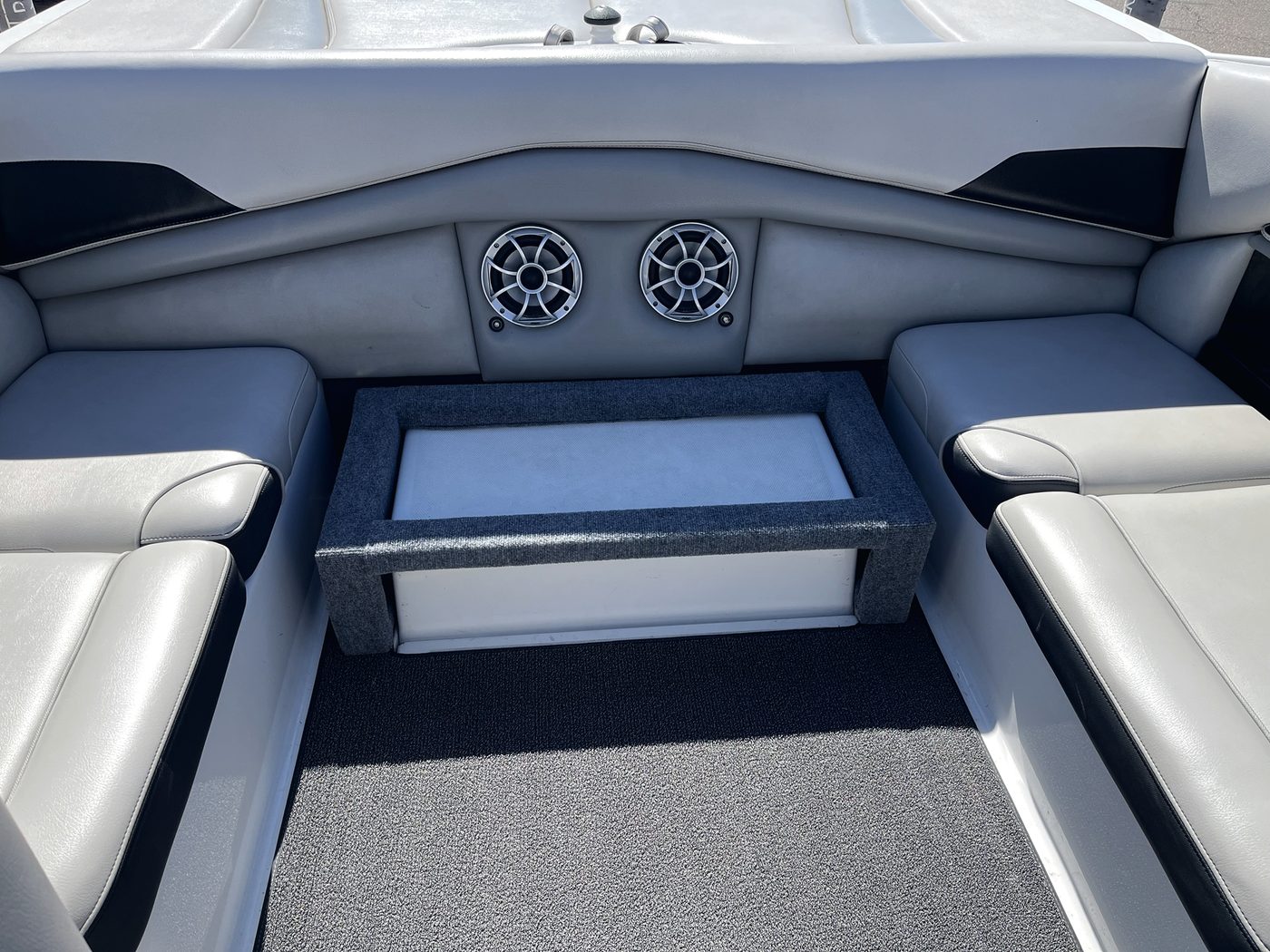 Finished carpeted seat base installed in a wake boat's rear lounge